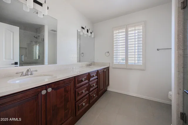 a bathroom with a granite countertop double vanity sink a large mirror and a bathtub