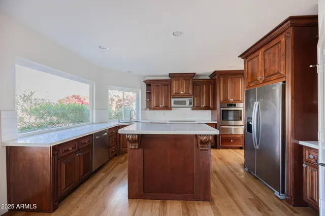 a kitchen with stainless steel appliances granite countertop a stove a refrigerator and a wooden floors