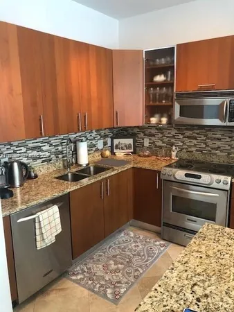 a kitchen with stainless steel appliances granite countertop a stove a sink and a microwave