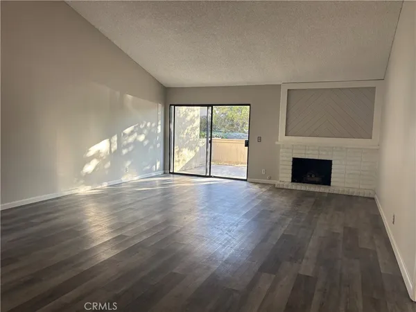 an empty room with wooden floor and fireplace