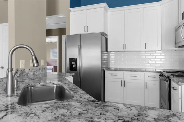 a kitchen with stainless steel appliances granite countertop a sink a stove and a refrigerator