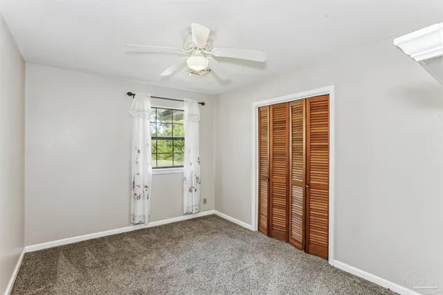 an empty room with a ceiling fan and a window