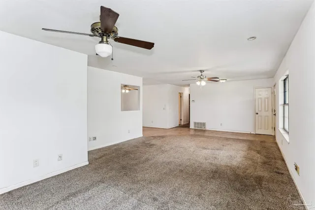 an empty room with a ceiling fan and a window