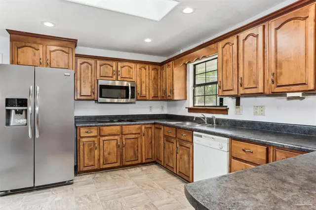 a kitchen with stainless steel appliances granite countertop a refrigerator a stove top oven and a sink