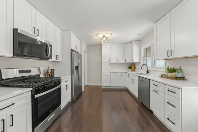 a kitchen with cabinets stainless steel appliances and wooden floor