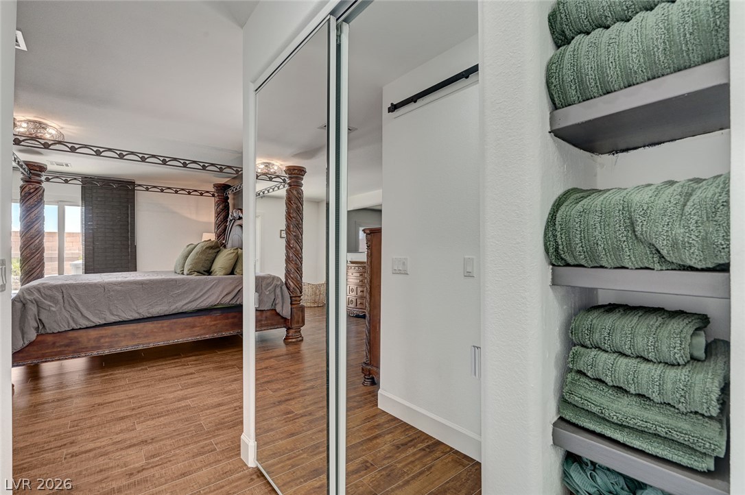 1072 Reed Point Court Henderson, NV 89002 - Photo 35 of 60 Rich hardwood-style flooring extends into this spacious bedroom, featuring a unique four-poster bed and mirrored closet doors.