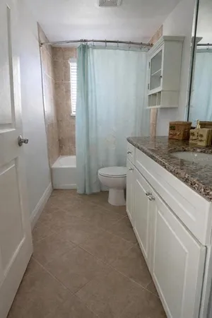 a bathroom with a granite countertop sink a toilet and shower