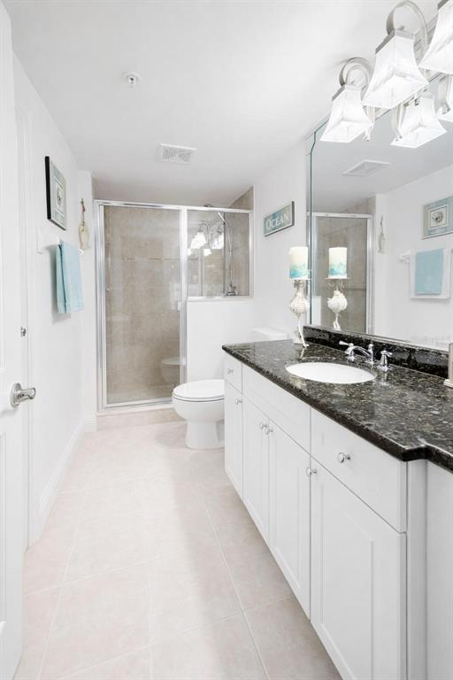 420 Harding Avenue, Unit 301 Cocoa Beach, FL 32931 - Photo 22 of 57 a bathroom with a granite countertop sink a toilet a mirror and shower