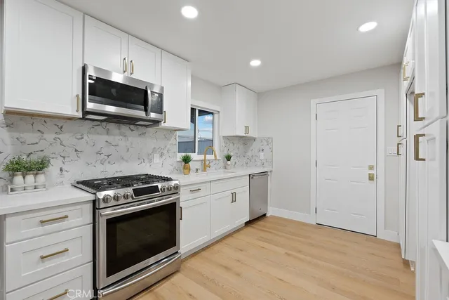 a view of a kitchen with white cabinets and wooden floor