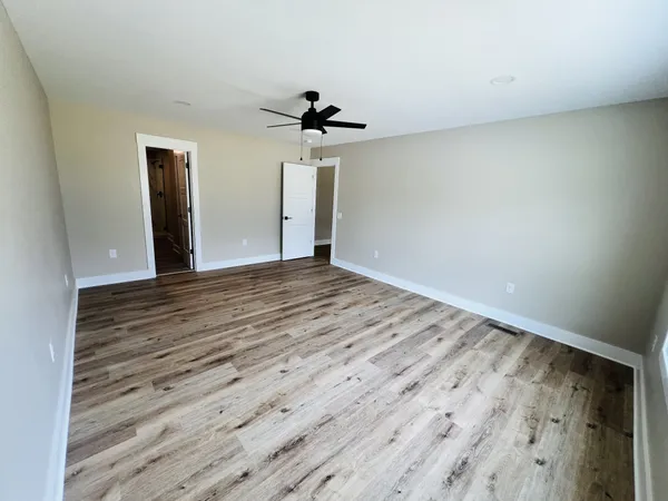 a view of a room with wooden floor and ceiling fan