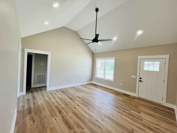 a view of an empty room with window and wooden floor