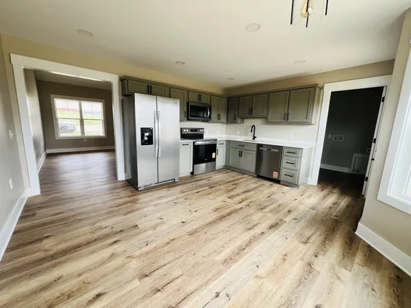 a open kitchen with a refrigerator a sink dishwasher and a stove with wooden floor