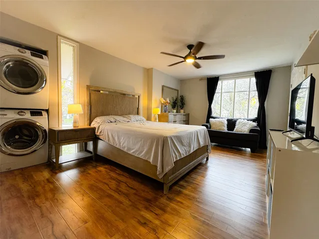a bedroom with a bed couch dresser and a large window