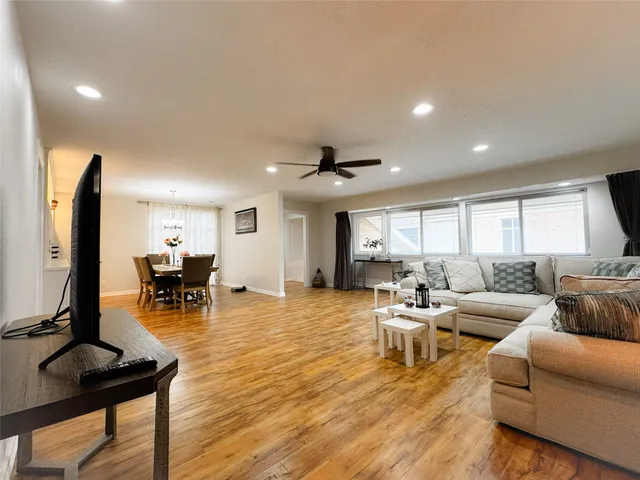 a living room with furniture and a flat screen tv with kitchen view