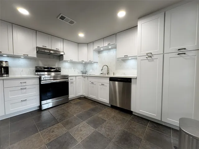 a kitchen with a stove sink and cabinets