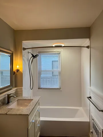 a bathroom with a granite countertop bathtub shower sink vanity and toilet