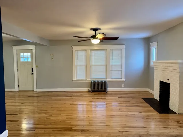 a view of empty room with wooden floor and fireplace