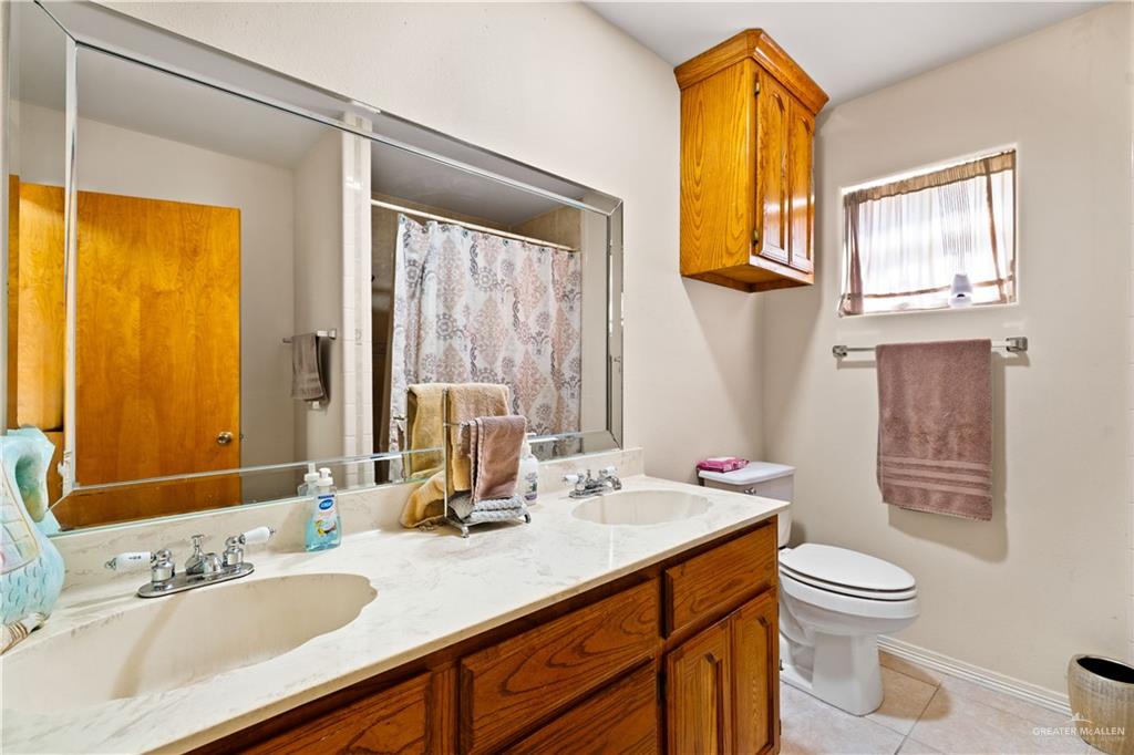 501 South Greene Road Mission, TX 78572 - Photo 16 of 28 a bathroom with a granite countertop sink toilet and shower