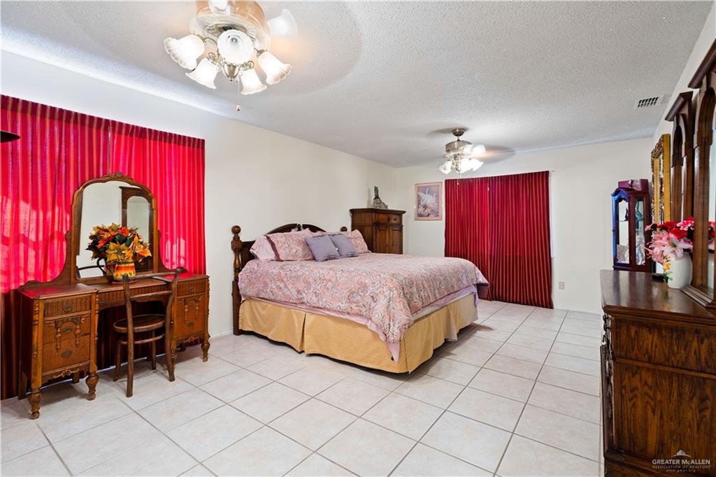 501 South Greene Road Mission, TX 78572 - Photo 17 of 28 a bedroom with a bed and a chandelier