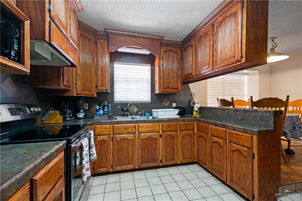 501 South Greene Road Mission, TX 78572 - Photo 9 of 28 a kitchen with stainless steel appliances granite countertop a sink stove and cabinets