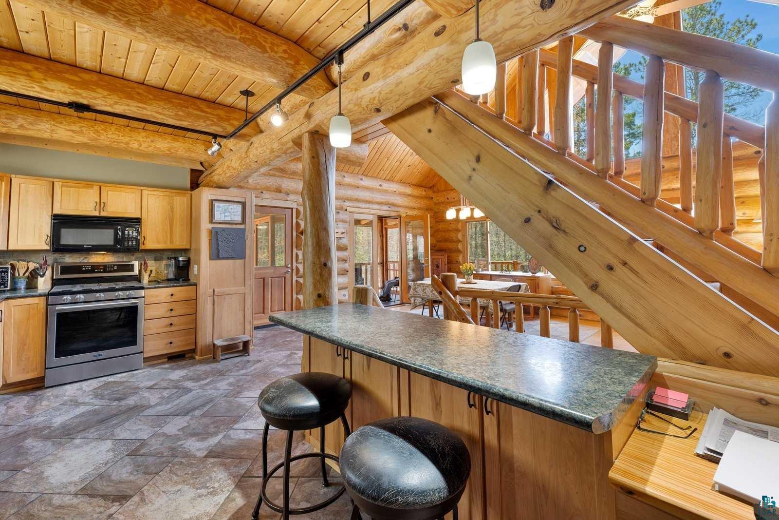 12957 West Ridge Road Ely, MN 55731 - Photo 5 of 41 Kitchen featuring stainless steel range with gas stovetop, black microwave, wood ceiling, dark countertops, and rustic walls