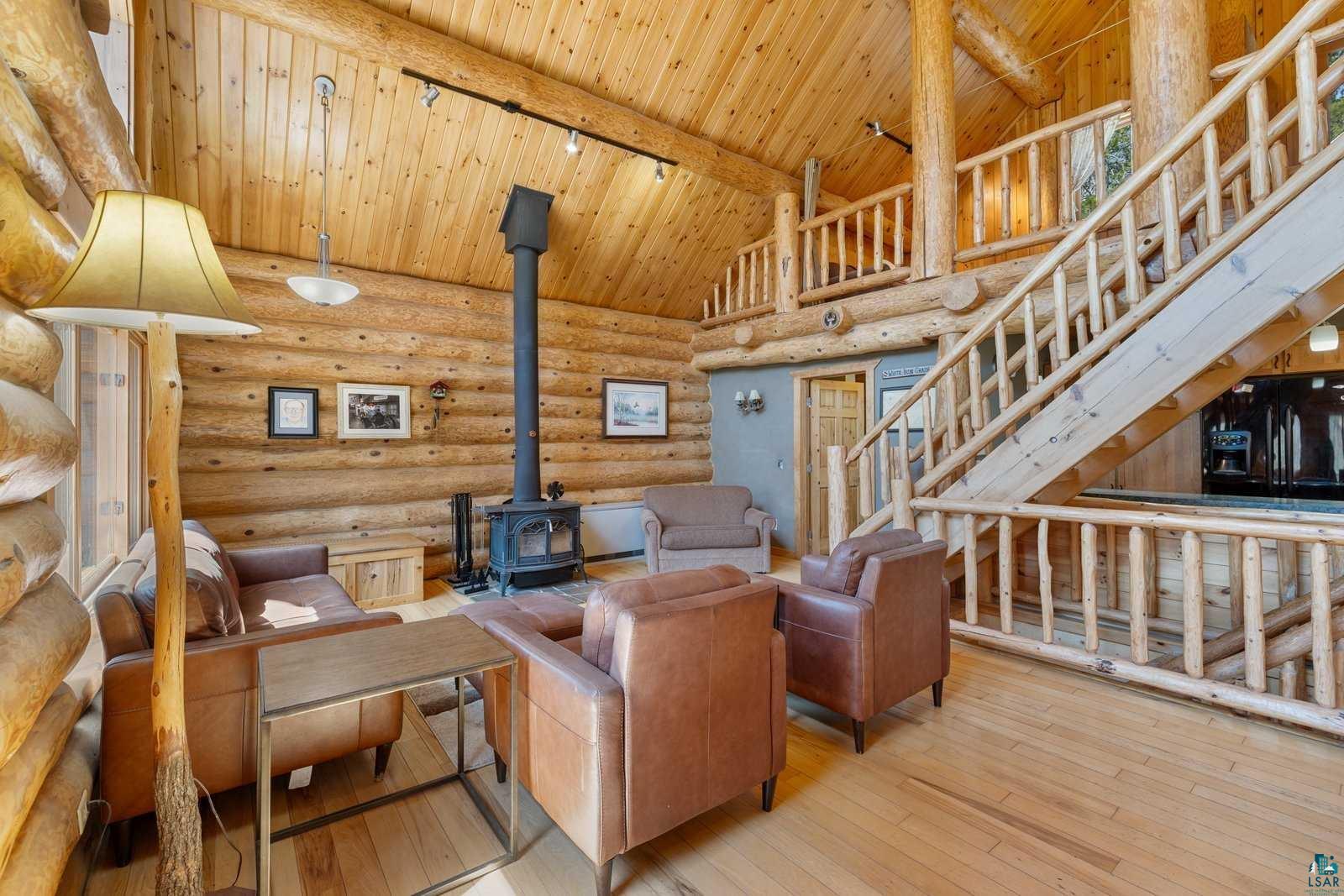 12957 West Ridge Road Ely, MN 55731 - Photo 9 of 41 Living room with a wood stove, stairway, beamed ceiling, wood ceiling, and rustic walls