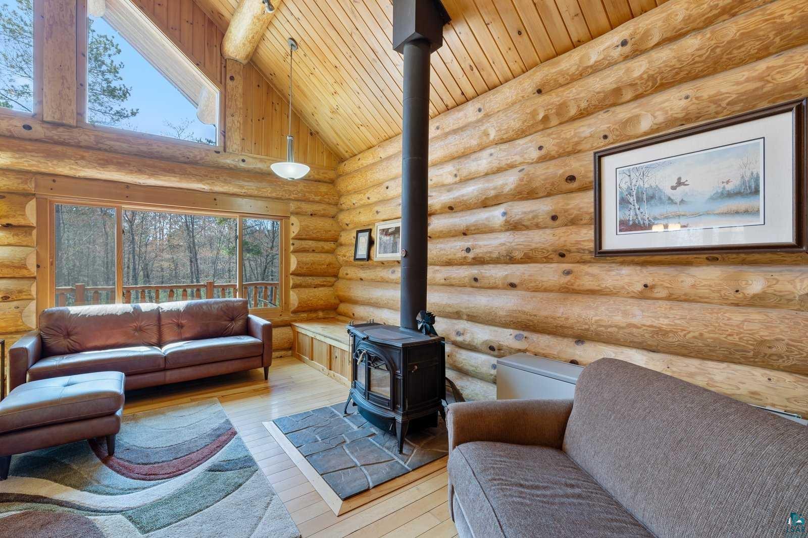 12957 West Ridge Road Ely, MN 55731 - Photo 10 of 41 Living room with wooden ceiling, a wood stove, rustic walls, and light wood-style floors
