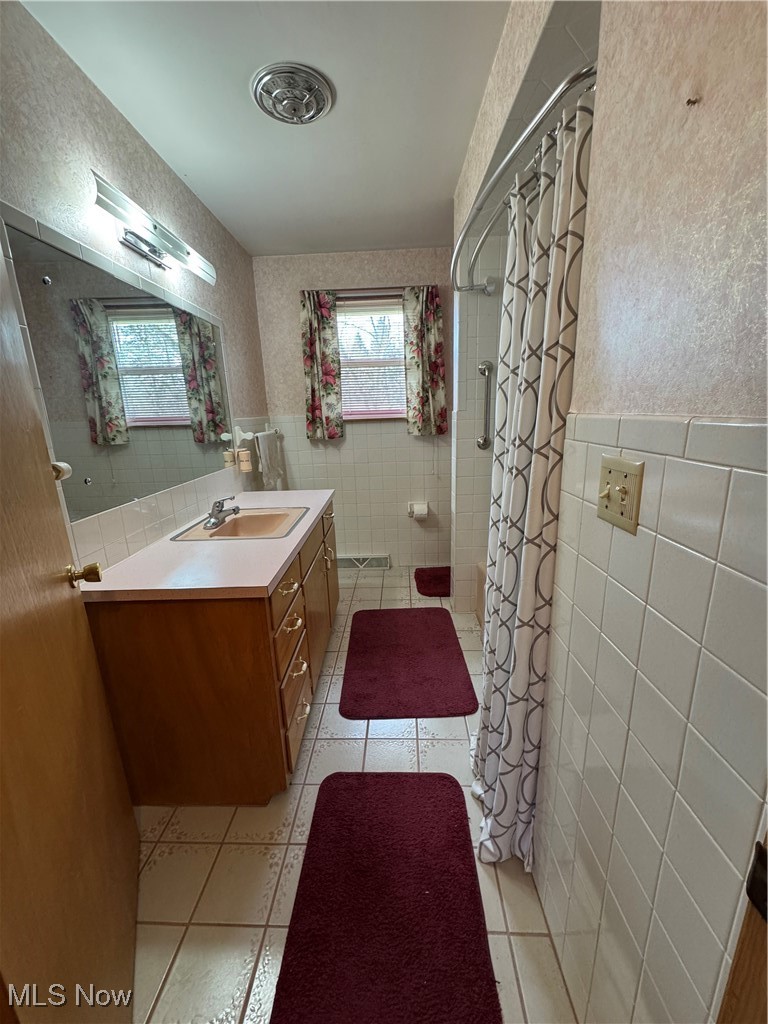 3919 New Road Youngstown, OH 44515 - Photo 5 of 16 Bathroom featuring curtained shower, tile patterned flooring, a wainscoted wall, and tile walls