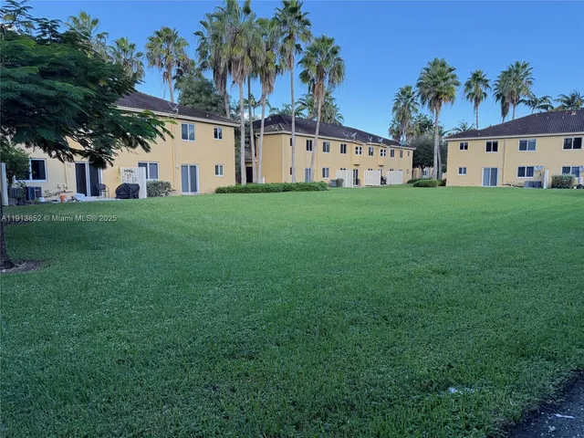 a view of a white house with a big yard and large trees