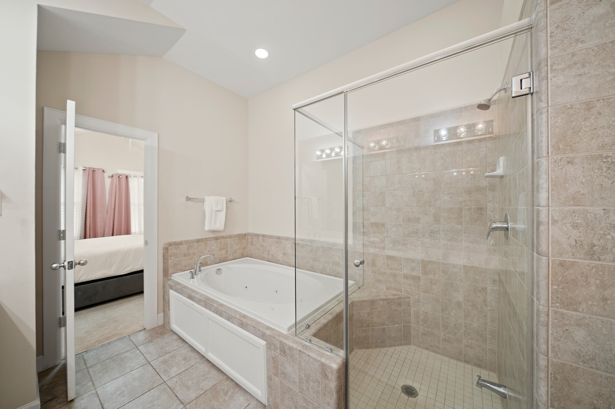 8705 Bryam Street, Unit 104 Houston, TX 77061 - Photo 12 of 16 Relax in the master bathroom oversized soaking tub or refresh in the glass-enclosed walk-in shower, both surrounded by neutral tile finishes.