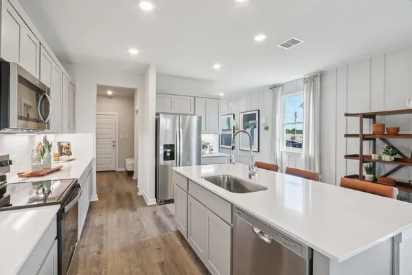 a large kitchen with stainless steel appliances lots of counter space and wooden floor