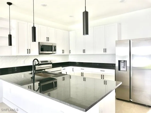 a kitchen with stainless steel appliances granite countertop a sink a stove and a refrigerator