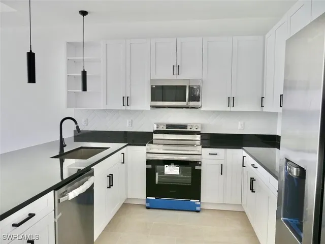 a kitchen with granite countertop white cabinets and stainless steel appliances