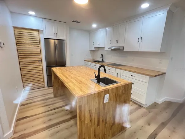a kitchen with stainless steel appliances a sink a refrigerator and cabinets