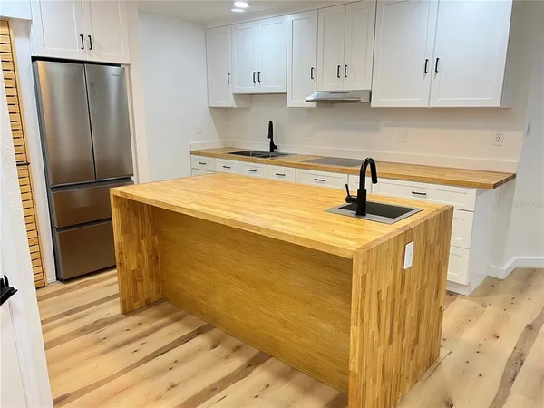 a kitchen with stainless steel appliances granite countertop a sink a refrigerator and white cabinets