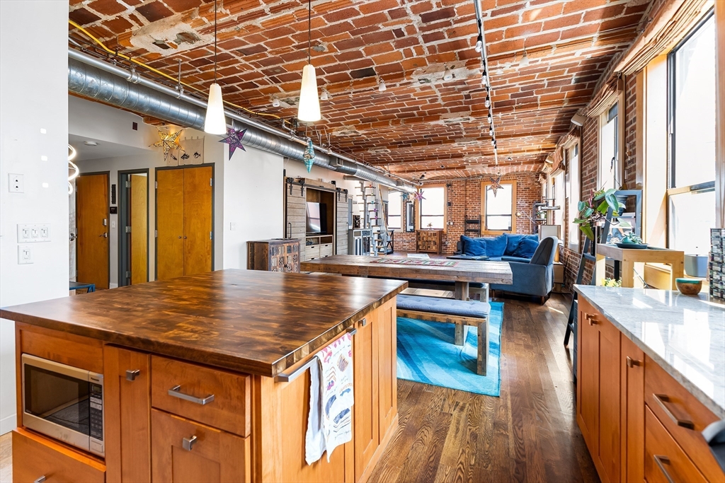 121-123 Beach Street, Unit 801 Boston, MA 02111 - Photo 5 of 28 a kitchen with stainless steel appliances granite countertop a sink and wooden floors