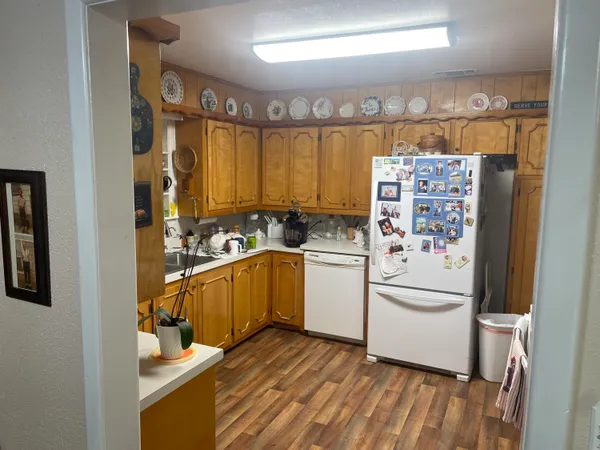 a kitchen with a stove a refrigerator and a dining table with wooden floor