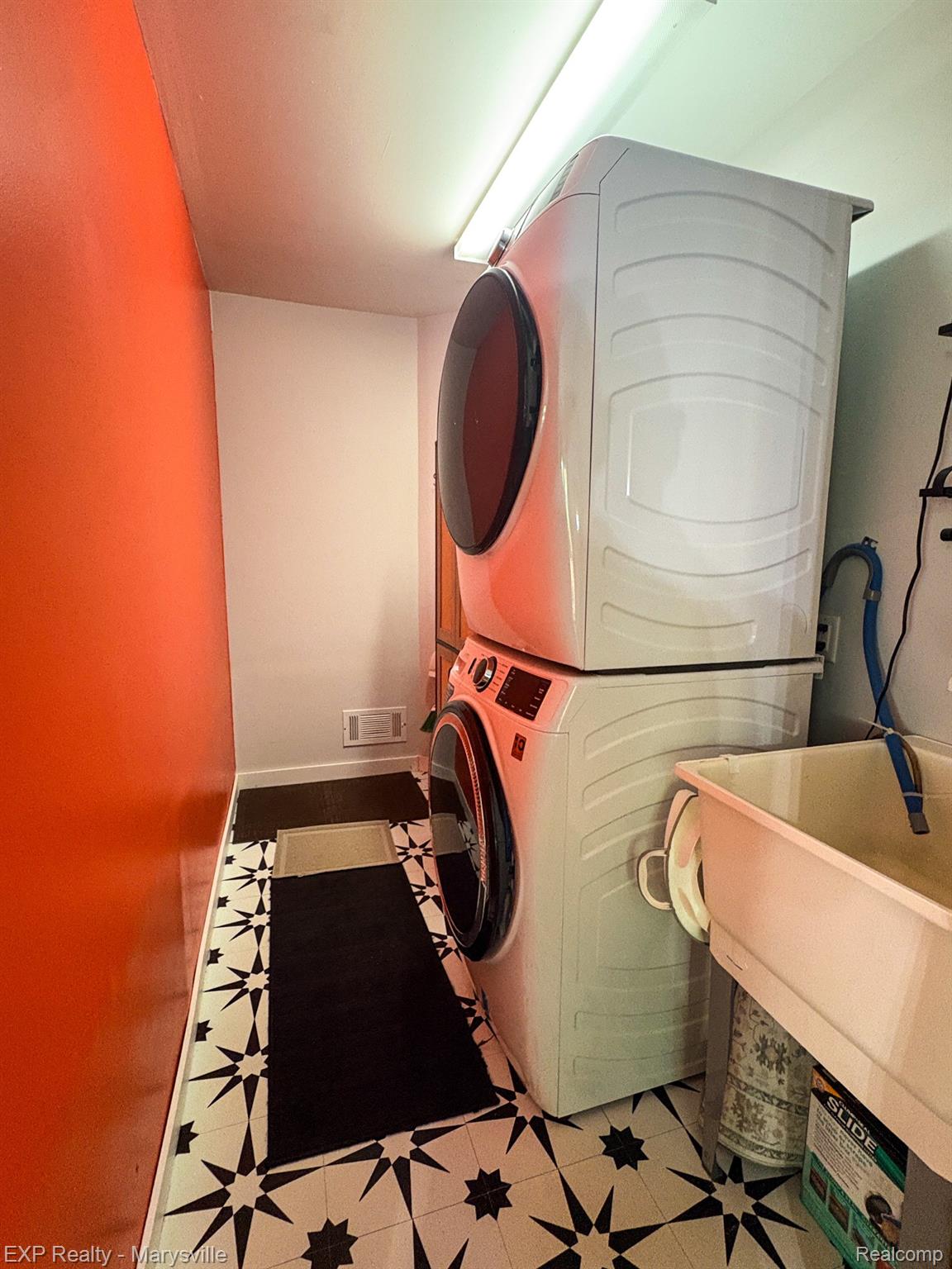 5538 Klettner Road St. Clair, MI 48079 - Photo 16 of 46 Laundry area featuring a stacked washer and dryer unit, patterned floor tiles, a utility sink, and wall-mounted lighting