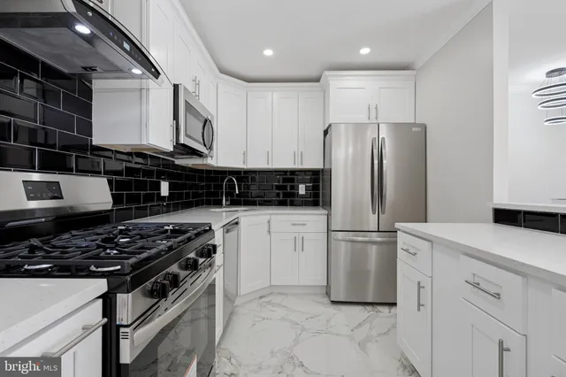 a kitchen with stainless steel appliances granite countertop a stove a refrigerator and a sink