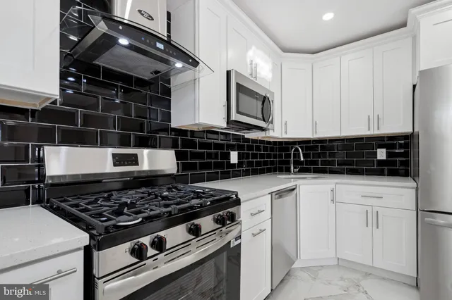 a kitchen with white cabinets and appliances