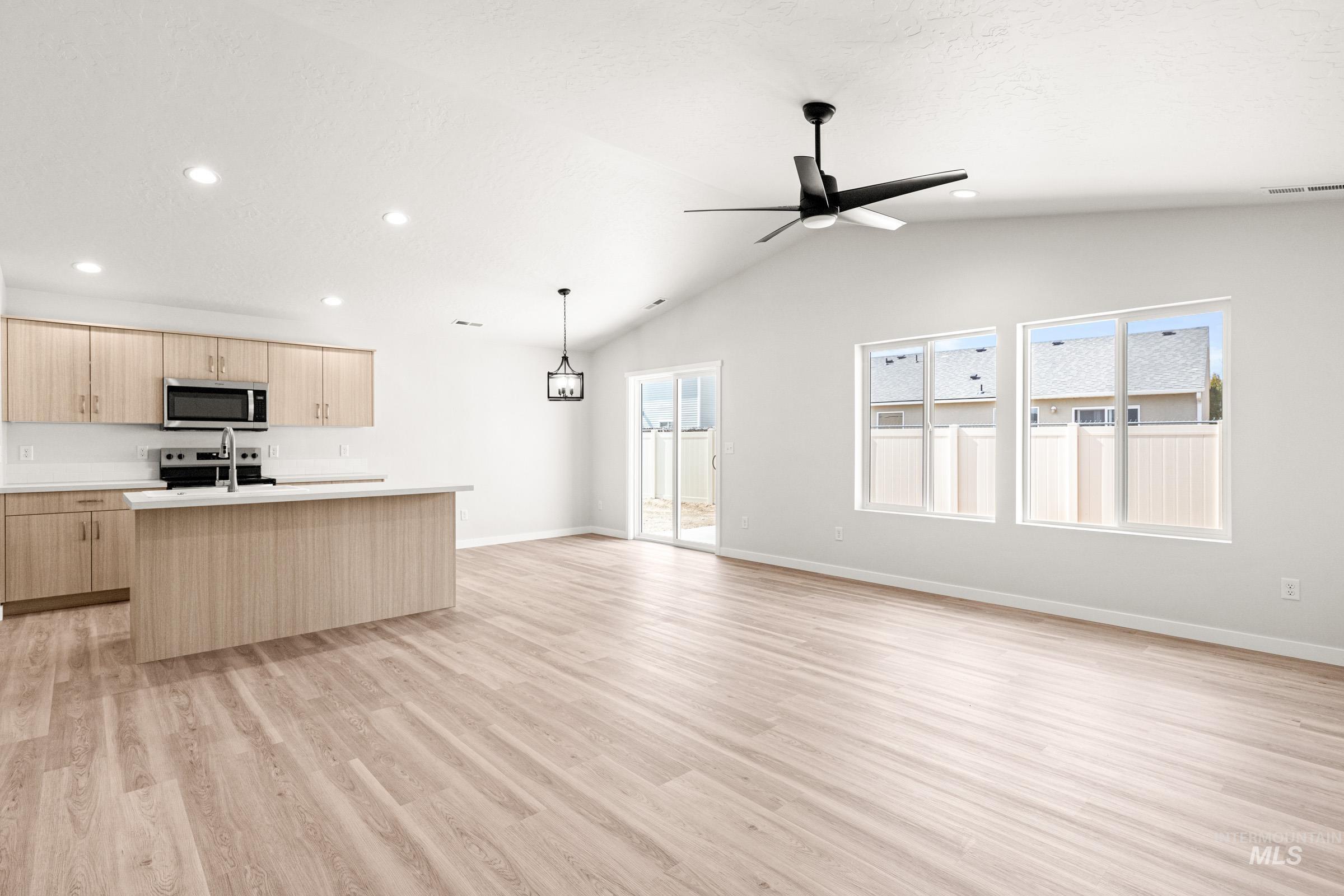 13736 Inman Court Caldwell, ID 83607 - Photo 19 of 20 Kitchen featuring light wood finish cabinets, open floor plan, a kitchen island with sink, light countertops, and light wood-style floors