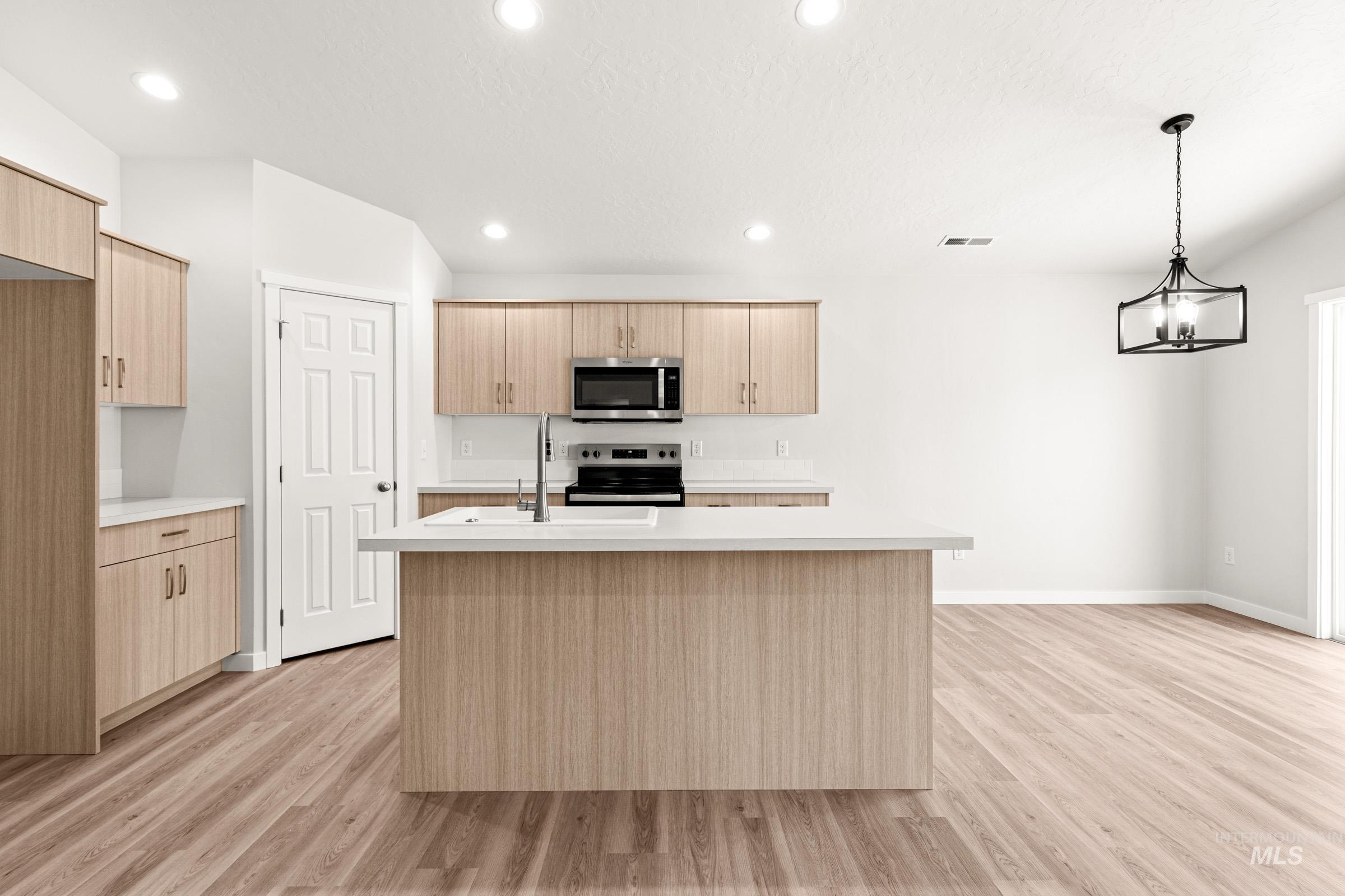 13736 Inman Court Caldwell, ID 83607 - Photo 3 of 20 Kitchen with a kitchen island with sink, light countertops, light wood-style flooring, and stainless steel appliances