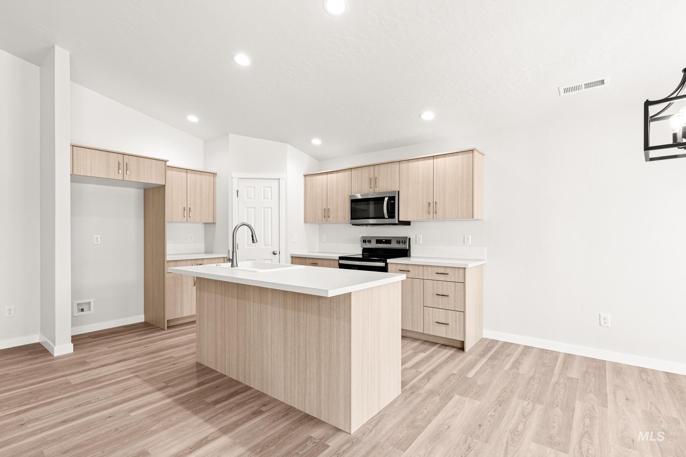 13736 Inman Court Caldwell, ID 83607 - Photo 5 of 20 Kitchen featuring an island with sink, light countertops, light wood finish cabinetry, stainless steel appliances, and light wood-style flooring
