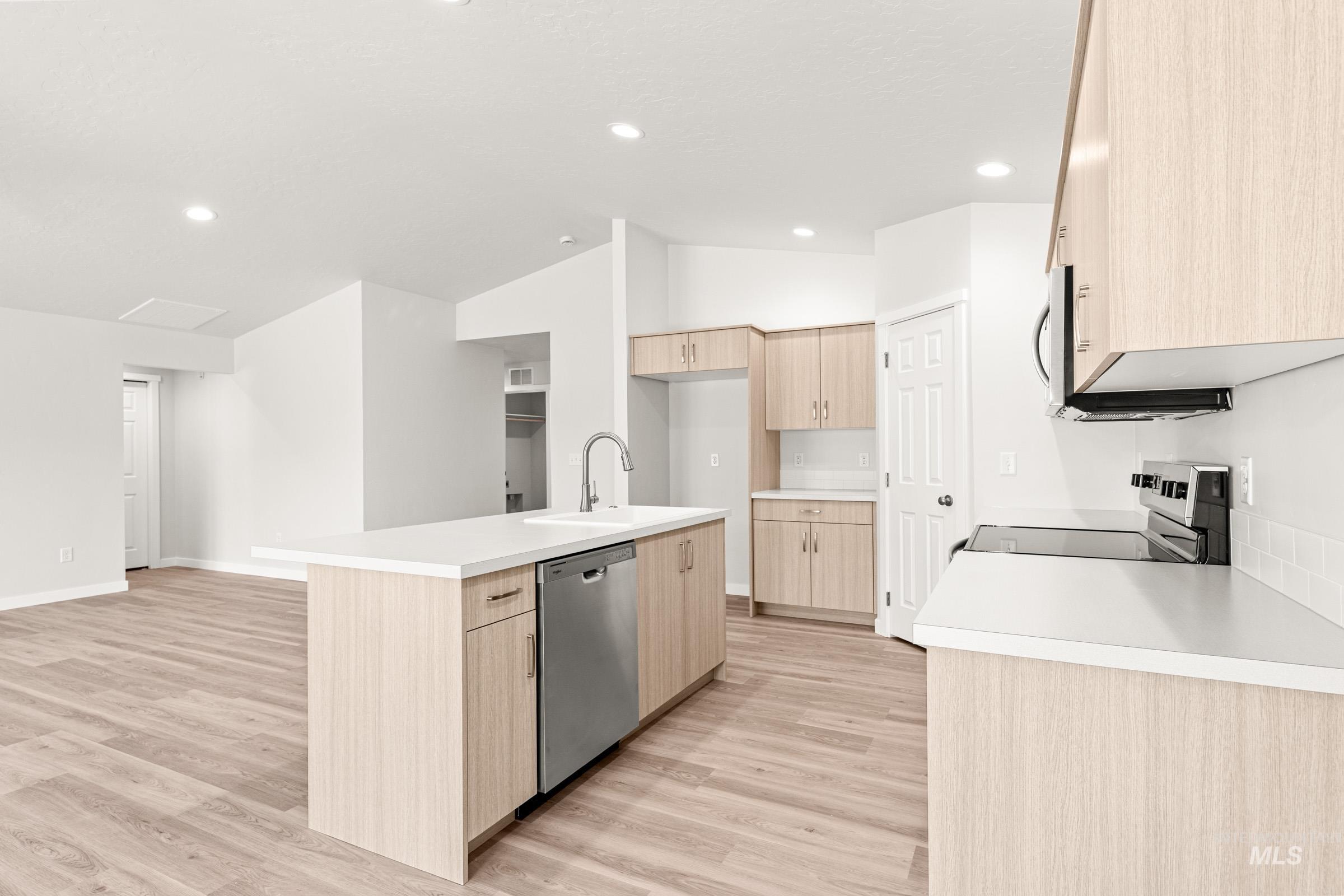 13736 Inman Court Caldwell, ID 83607 - Photo 7 of 20 Kitchen with light wood finish cabinetry, an island with sink, stainless steel appliances, light wood-type flooring, and vaulted ceiling