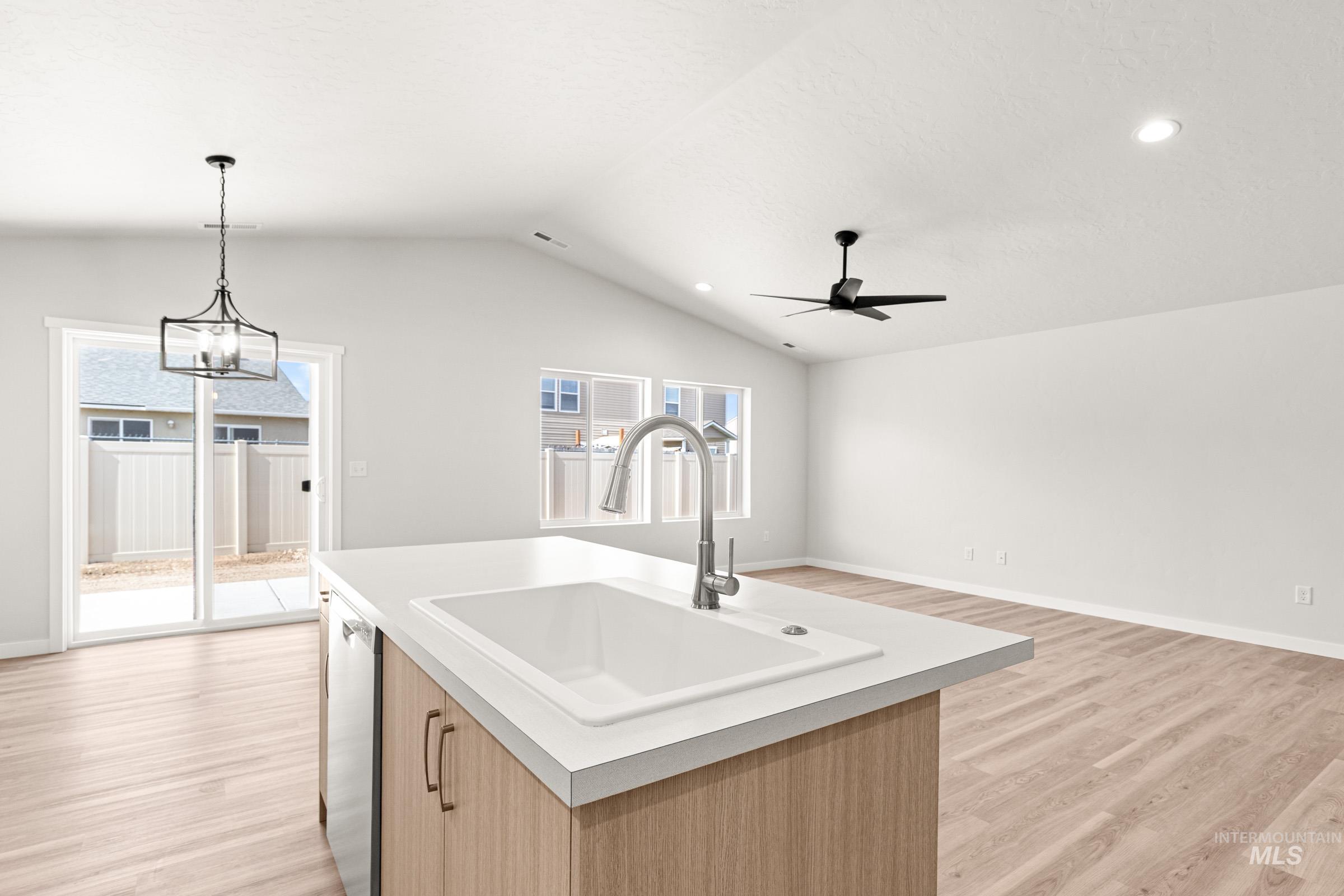 13736 Inman Court Caldwell, ID 83607 - Photo 18 of 20 Kitchen featuring light wood finished floors, open floor plan, light countertops, a center island with sink, and ceiling fan