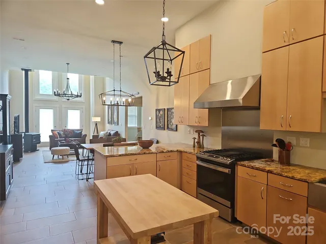 a kitchen with granite countertop a stove a sink a refrigerator and wooden floor