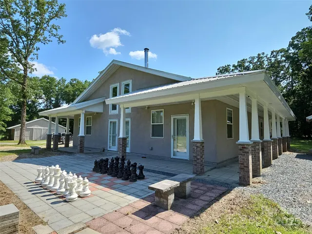 a front view of a house with a yard outdoor seating and covered with trees