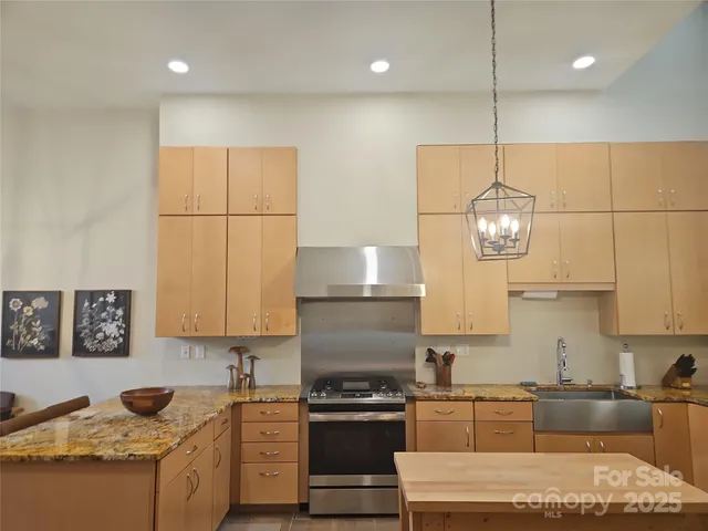 a kitchen with kitchen island granite countertop stainless steel appliances a stove sink and refrigerator