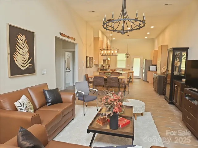 a living room with furniture kitchen view and a chandelier