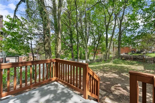 a backyard of a house with large trees and plants